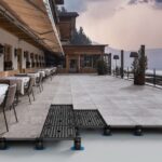 Tables_and_chairs_arranged_by_windows._Beautiful_outdoor_place_setting_at_restaurant_against_sky._Exterior_of_dining_hall_in_luxurious_ski_resort_during_sunset.