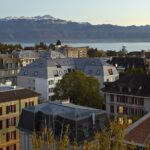 Blick auf Mehrfamilienhaus in Lausanne mit Genfer See und Alpen im Hintergrund
