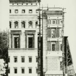 Bauen im Nationalsozialismus: Zwei schmale hohe Gebäude mit vielen Fenstern und Säulen eng nebeneinander. Rechtes Gebäude mit Gerüst.